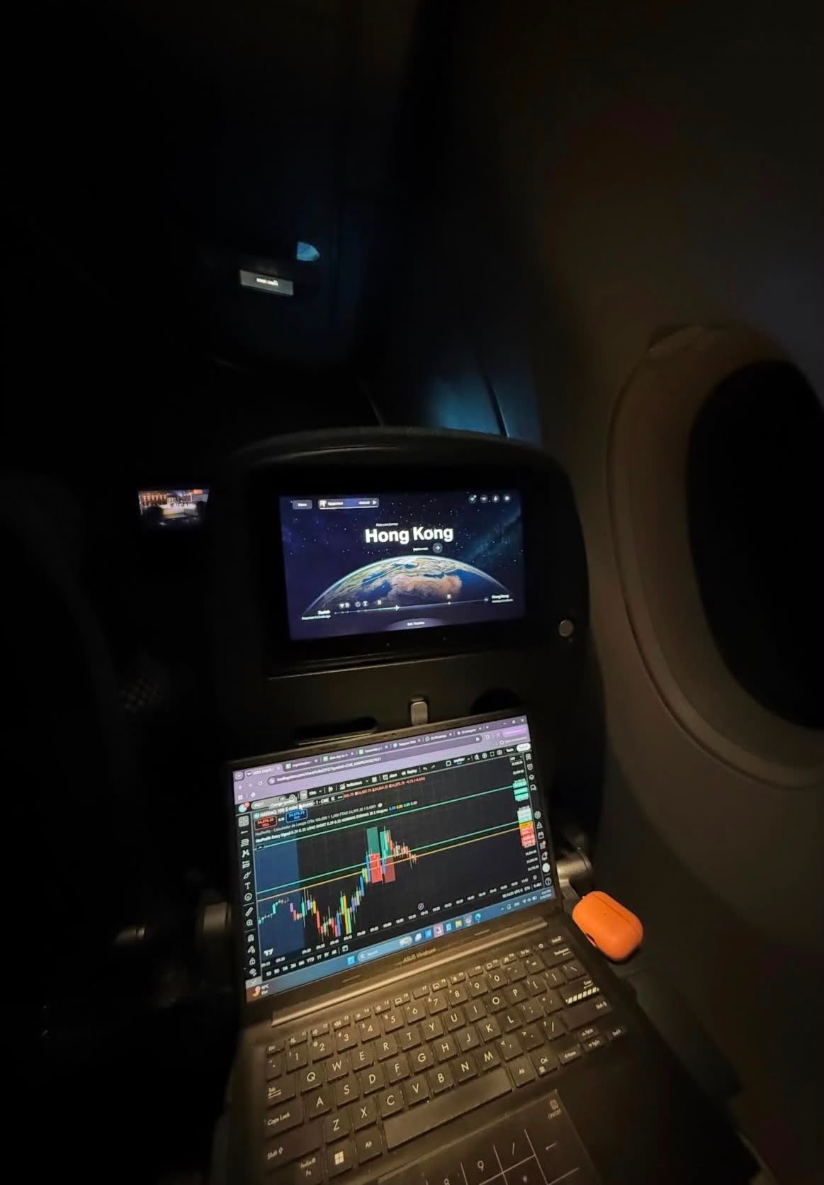 Uçak kabininde laptop ekranında grafik analizi ve Hong Kong uçuş haritası
